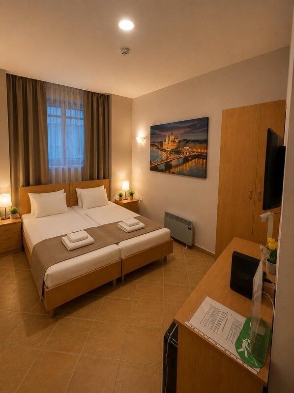 Une chambre d’hôtel avec un lit double, un bureau avec un ordinateur, une télévision, un tableau représentant un pont et une fenêtre avec des rideaux.