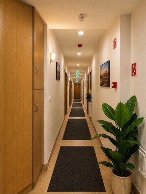A hotel corridor with wooden doors, black carpets, and potted plants. - Esprit Hotel Budapest (Budapest)