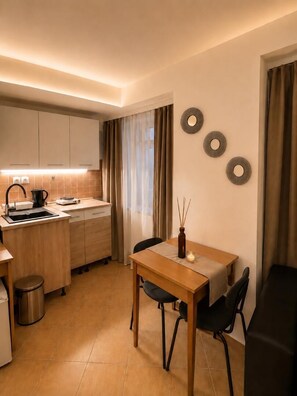 A compact kitchen with a dining table, chairs, and a small sink. - Esprit Hotel Budapest (Budapest)