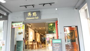 L’extérieur d’un café, avec une enseigne indiquant « Café hainanais » et un panneau affichant le menu à l’extérieur.