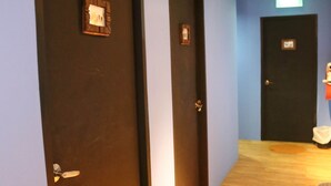 Un couloir avec trois portes fermées, un plancher en bois et un luminaire au plafond.