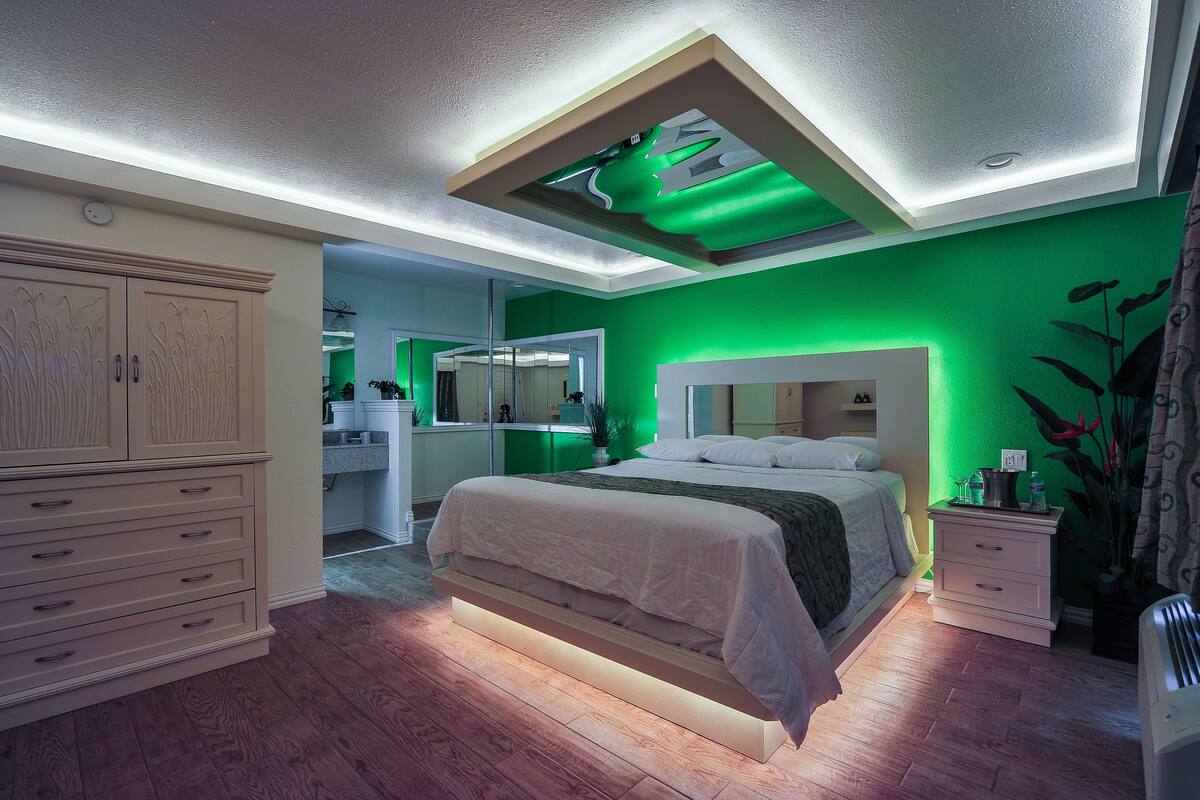 Un dormitorio con cama, mesitas de noche, cómoda y espejo.