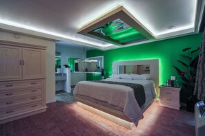 A bedroom with a bed, nightstands, a dresser, and a mirror. - Romantic Inn & Suites (Dallas)