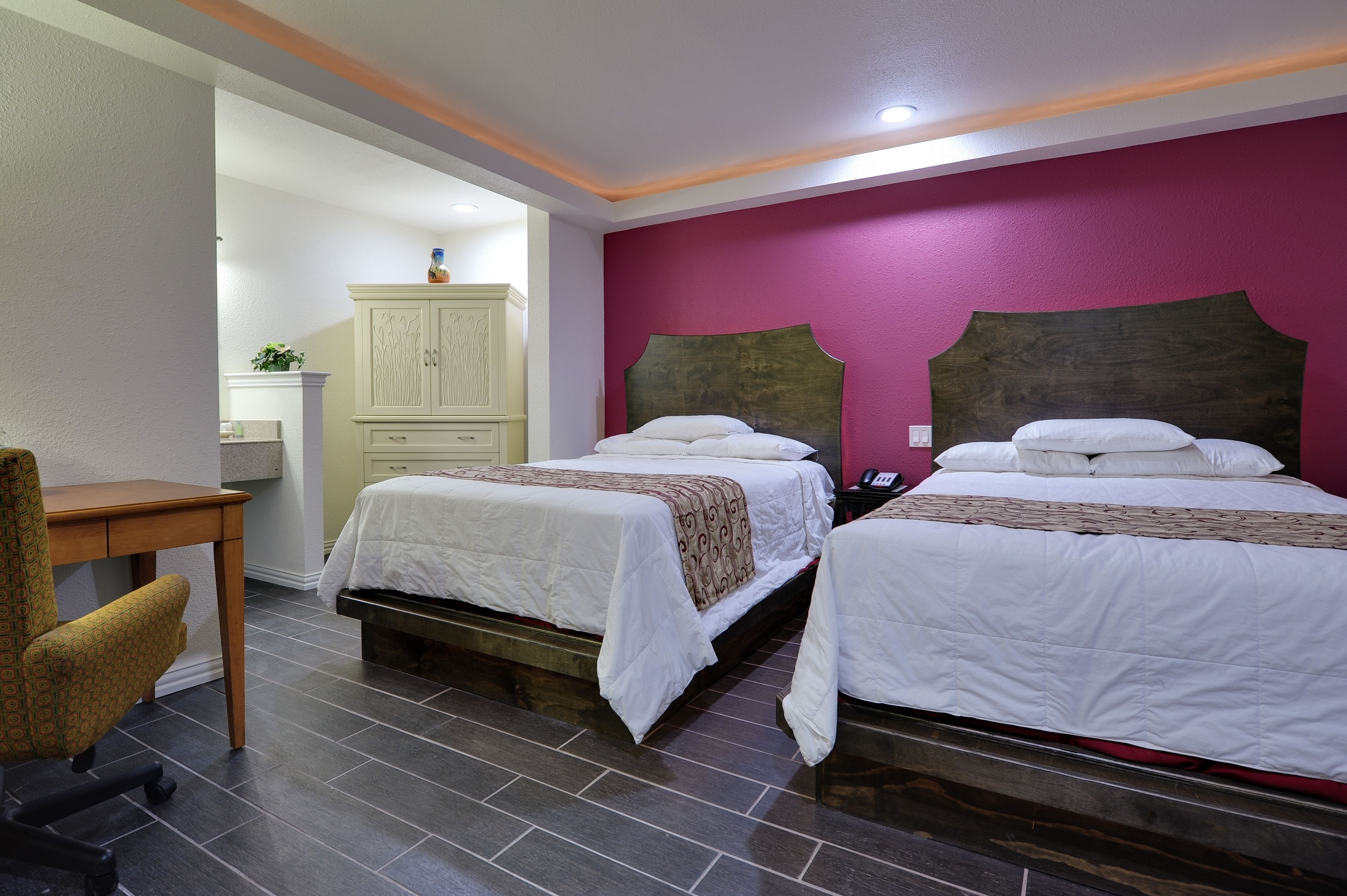 A hotel room with two beds, a desk, and a chair.