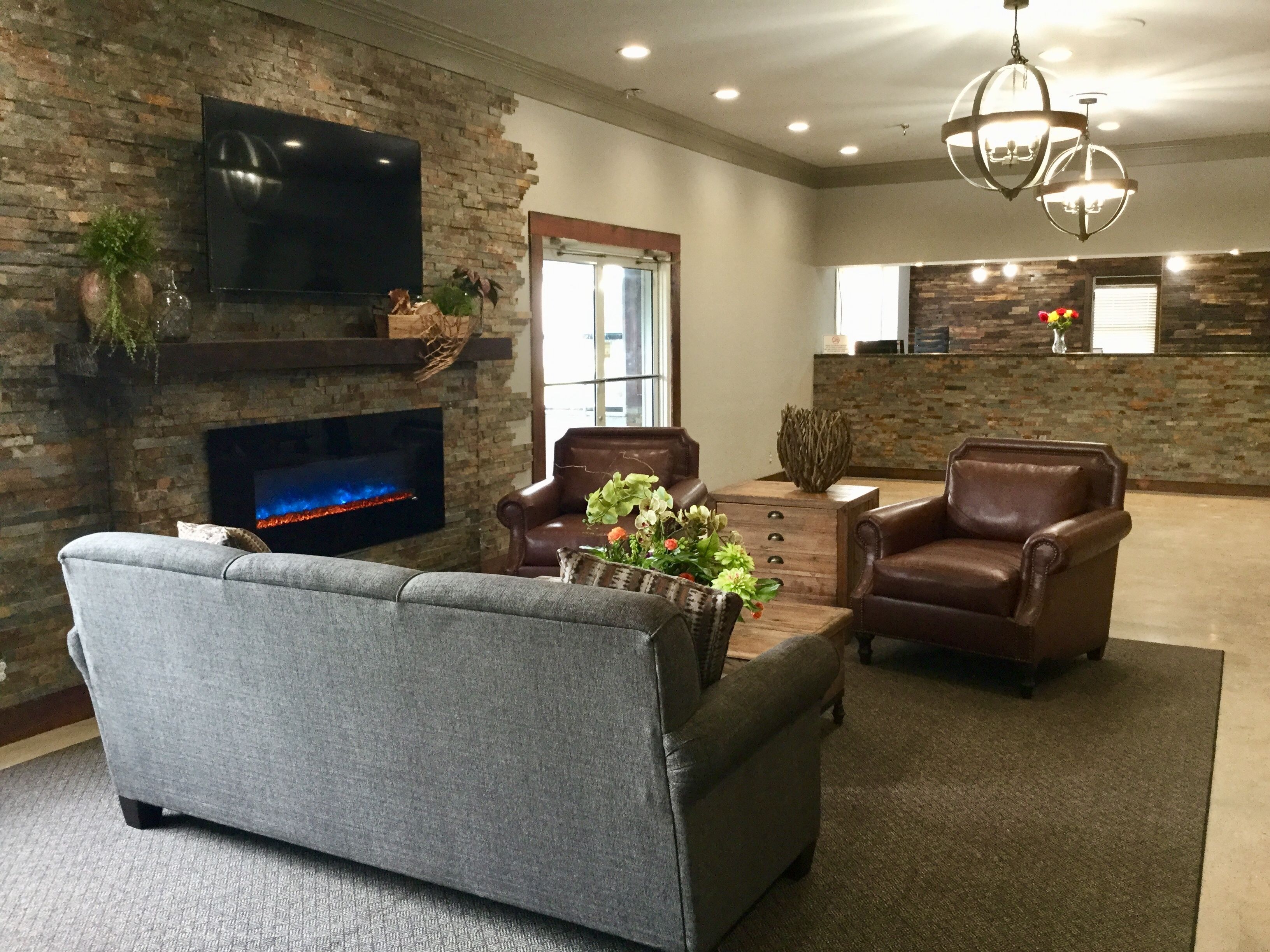 A modern living room with a fireplace, leather chairs, and a flat-screen TV.