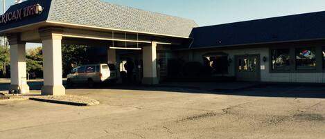 A parking lot with a building labeled "American Inn" and a van parked under a covered area.