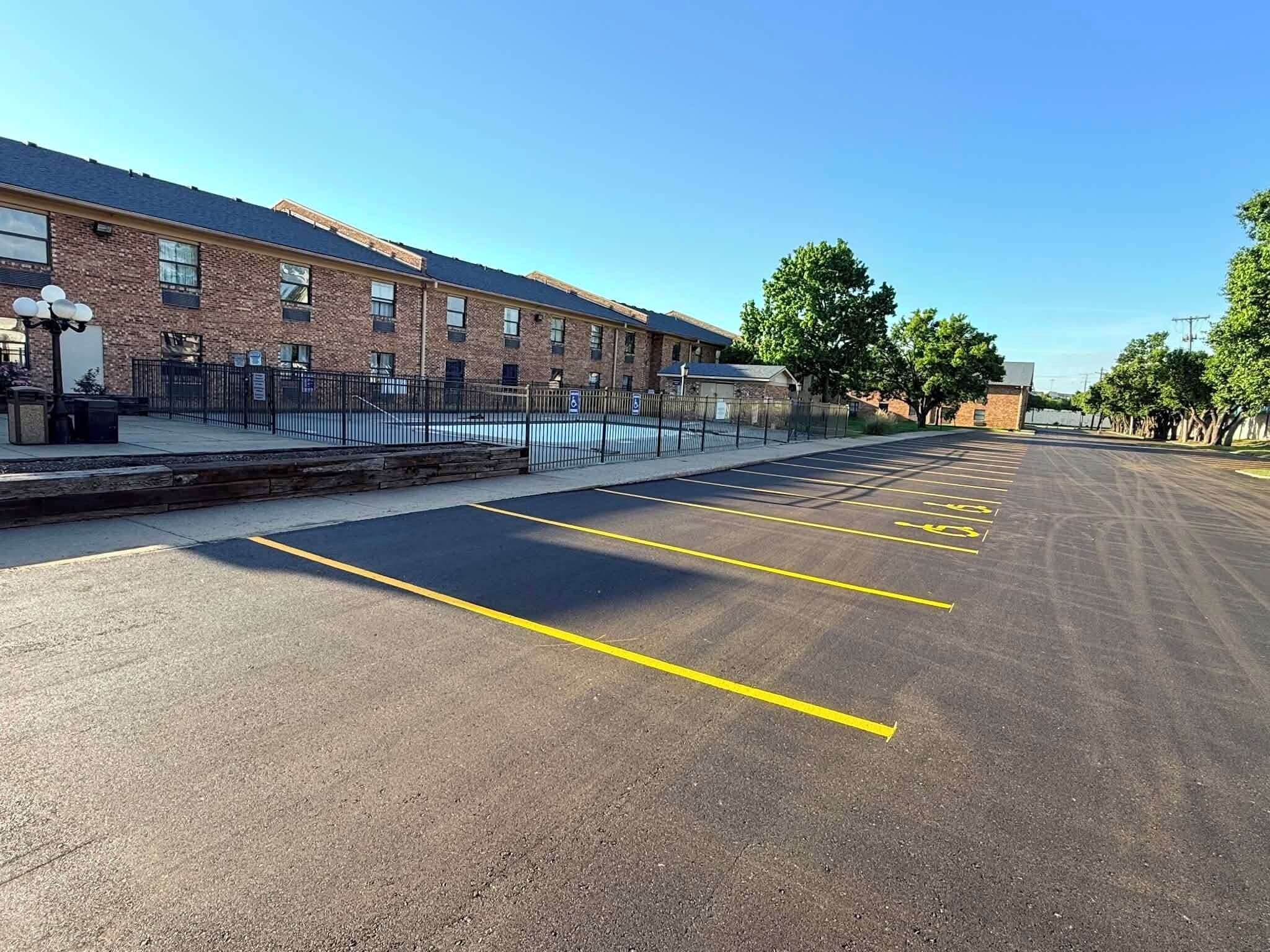 A parking lot with marked spaces, a brick building, and a clear sky.