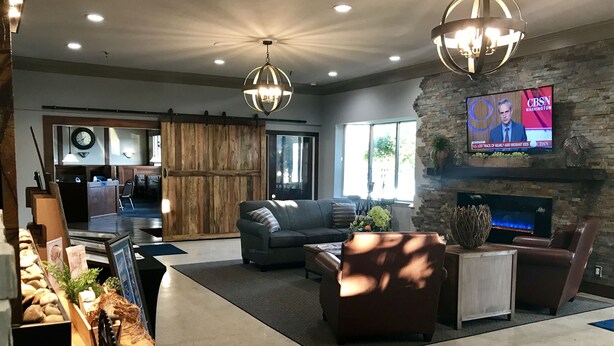 Un amplio espacio de sala de estar con chimenea, televisor y zona de asientos con sofá y sillones.