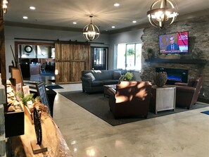 A spacious living area with a fireplace, a television, and a seating area with a sofa and chairs. - American Inn North Kansas City (North Kansas City)
