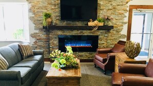 Una sala de estar con chimenea de piedra, sofás de cuero y una mesa de centro de madera.