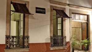Fachada de edificio con dos ventanas, cada una con un balcón de metal y un letrero arriba que dice "GERTRUDIS".