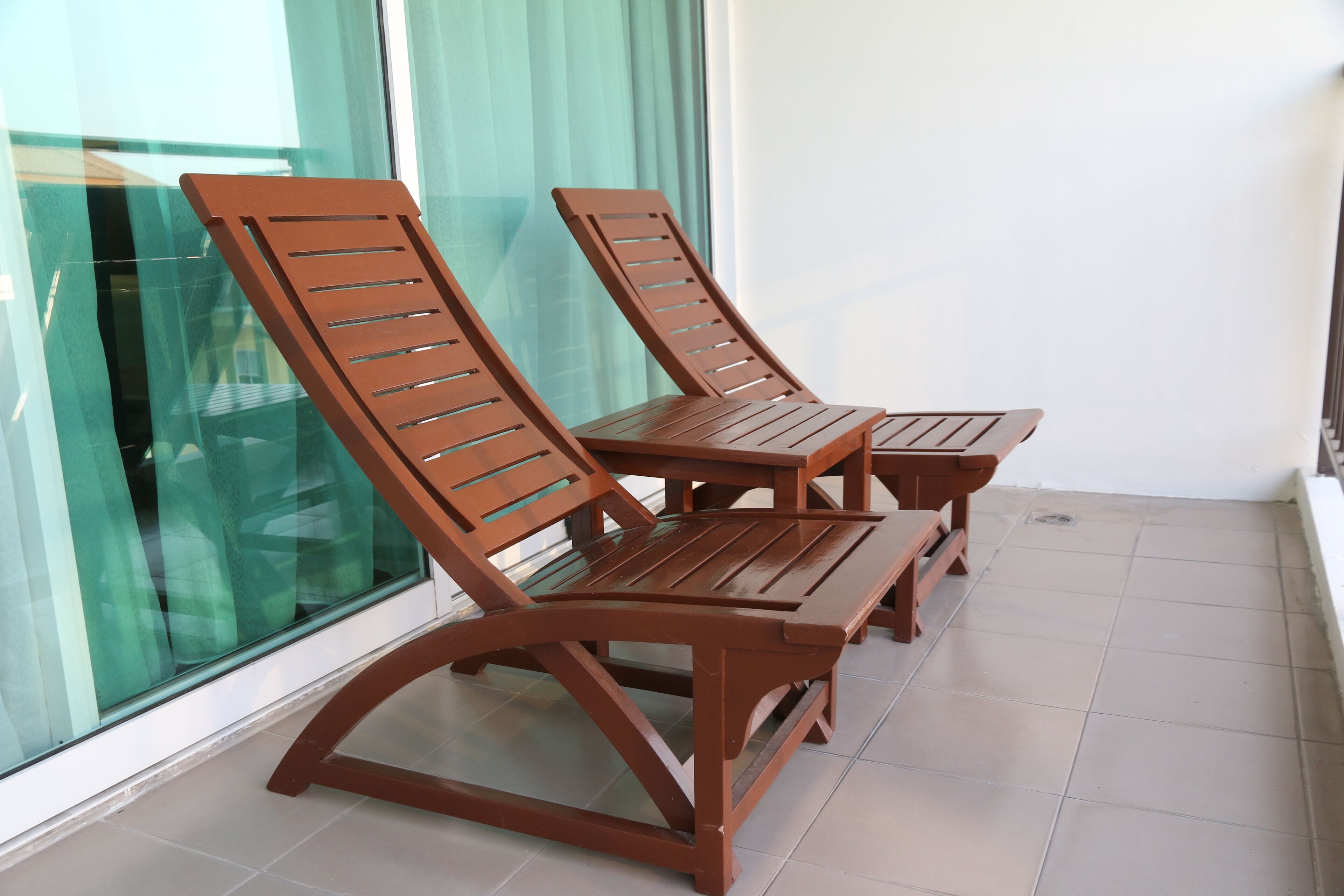 Un balcón con dos sillones de madera y una mesita.
