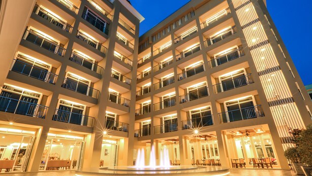 A multi-story hotel with a central courtyard featuring a fountain. - Crystal Palace Luxury Hotel (Pattaya)