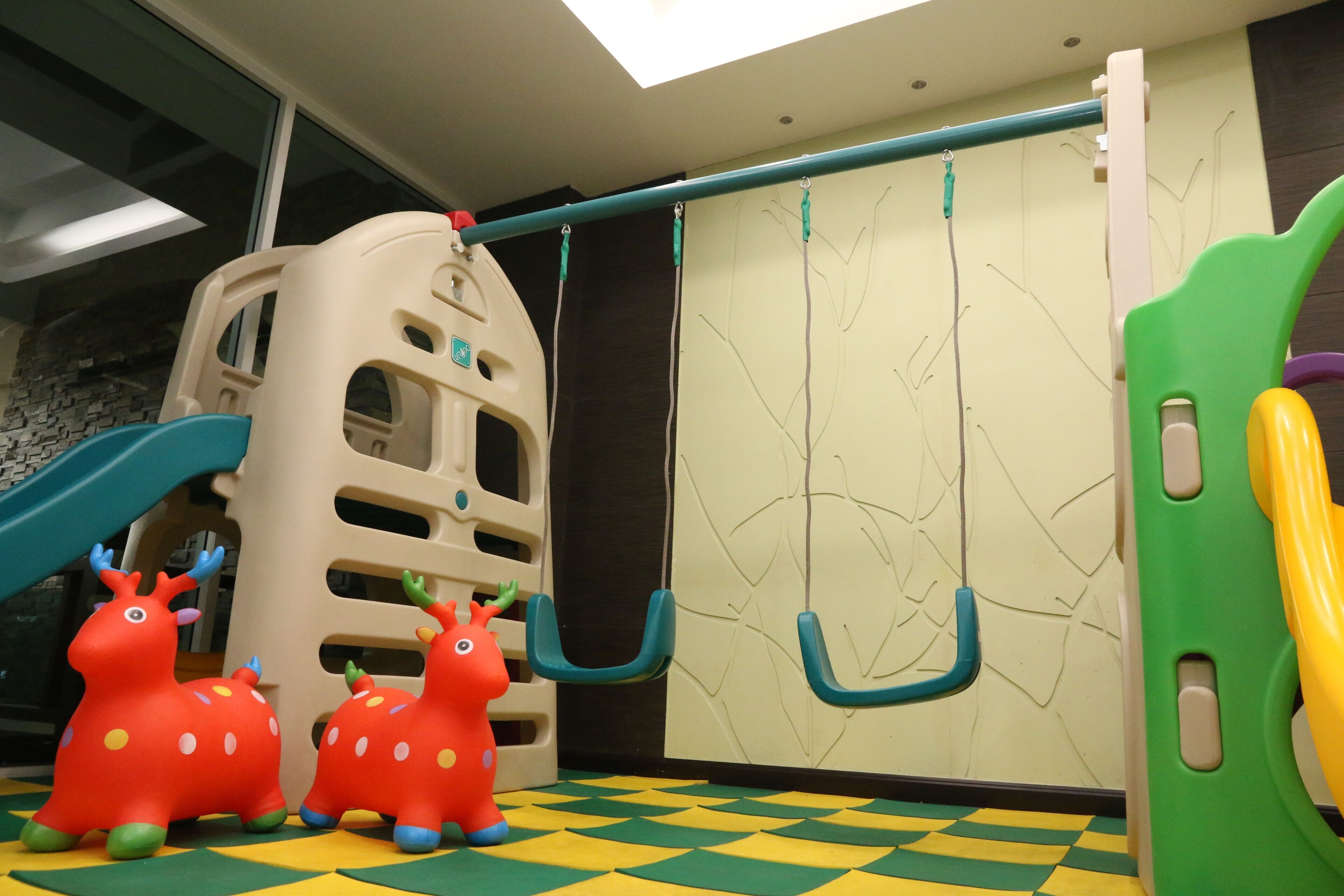 A children's play area with a climbing structure, a slide, and colorful animal figures.