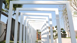 A pathway lined with white geometric structures, leading to a building with a modern design. - Crystal Palace Luxury Hotel (Pattaya)