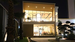 A two-story building with a modern design, featuring a well-lit entrance and a visible outdoor seating area. - Crystal Palace Luxury Hotel (Pattaya)