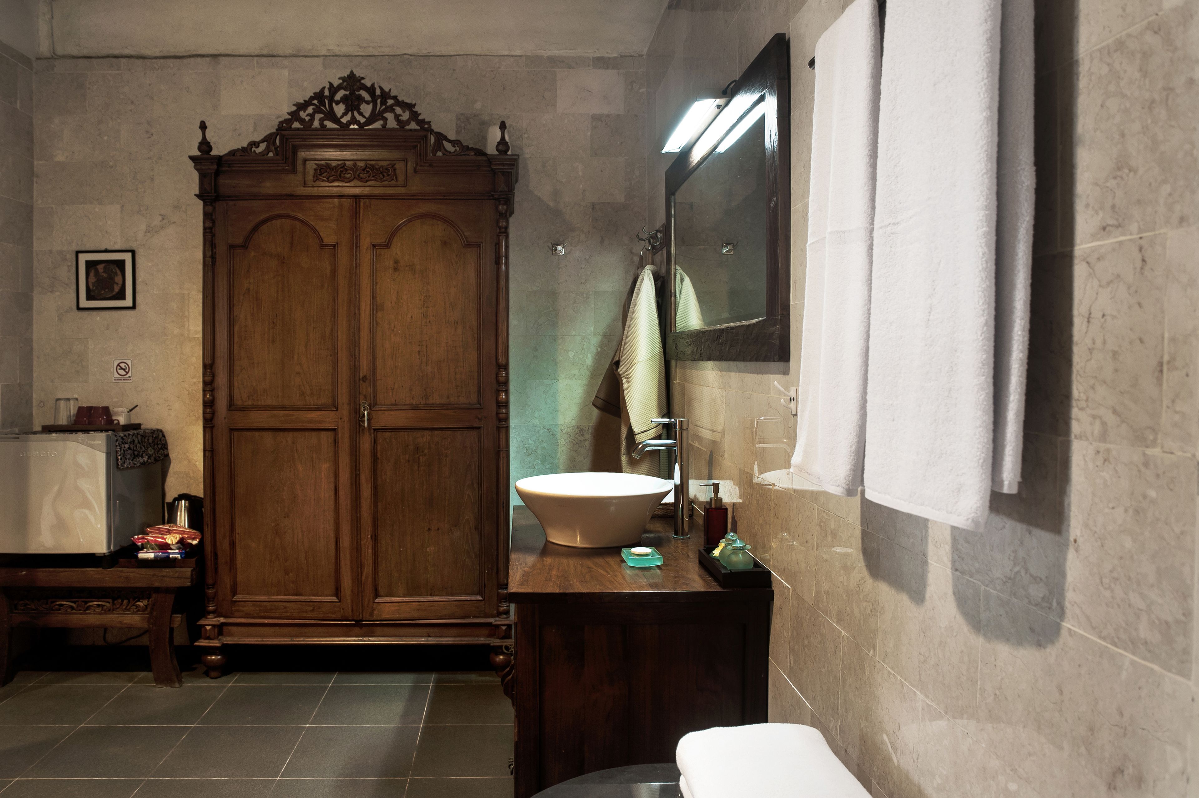 Un baño con un armario de madera, un lavabo de gran tamaño y un espejo.