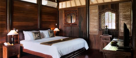 Een houten kamer met een groot bed, nachtkastjes, een spiegel en een televisie.