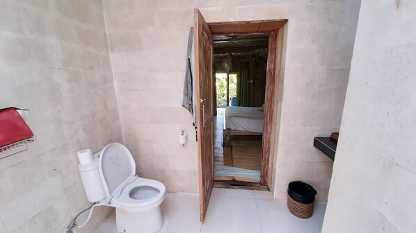 Un baño pequeño y funcional con inodoro, una bolsa roja y un cubo de basura.