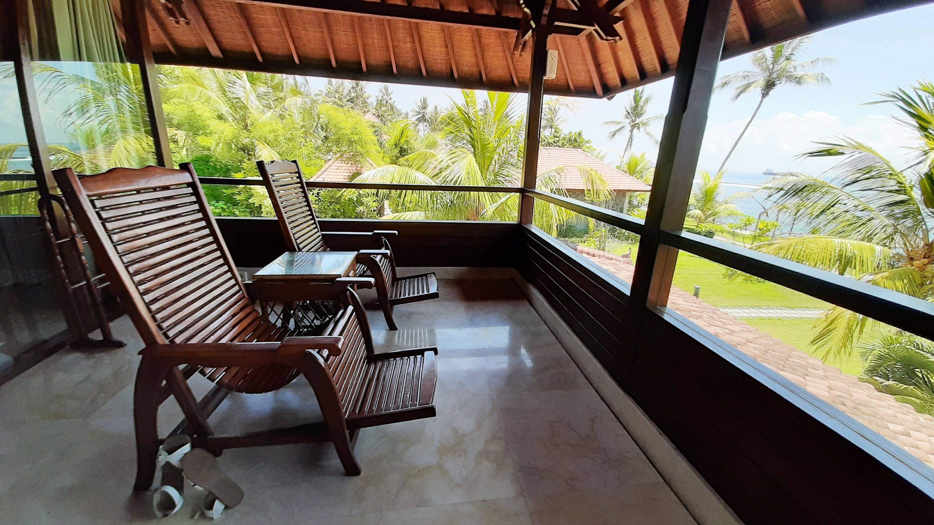 Un balcone con mobili in legno e vista su vegetazione tropicale.