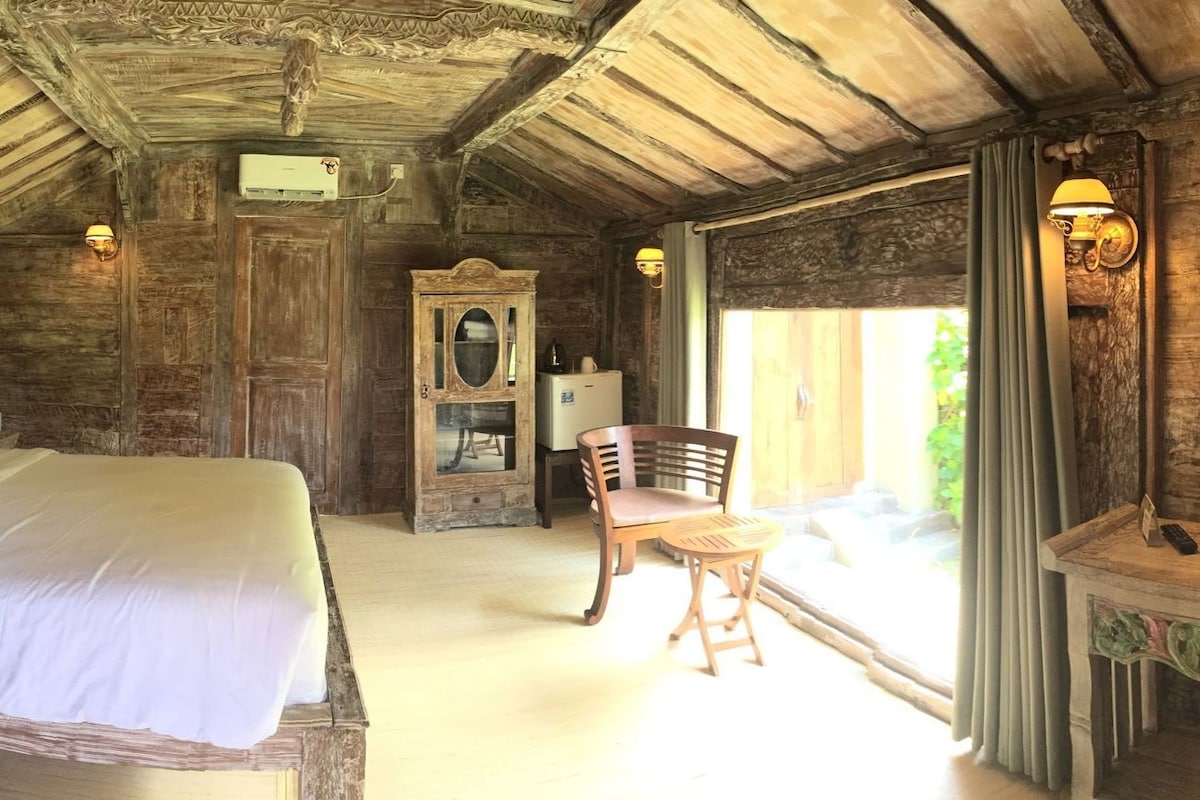 Una habitación rústica de madera con cama, televisor, armario de madera y una silla.