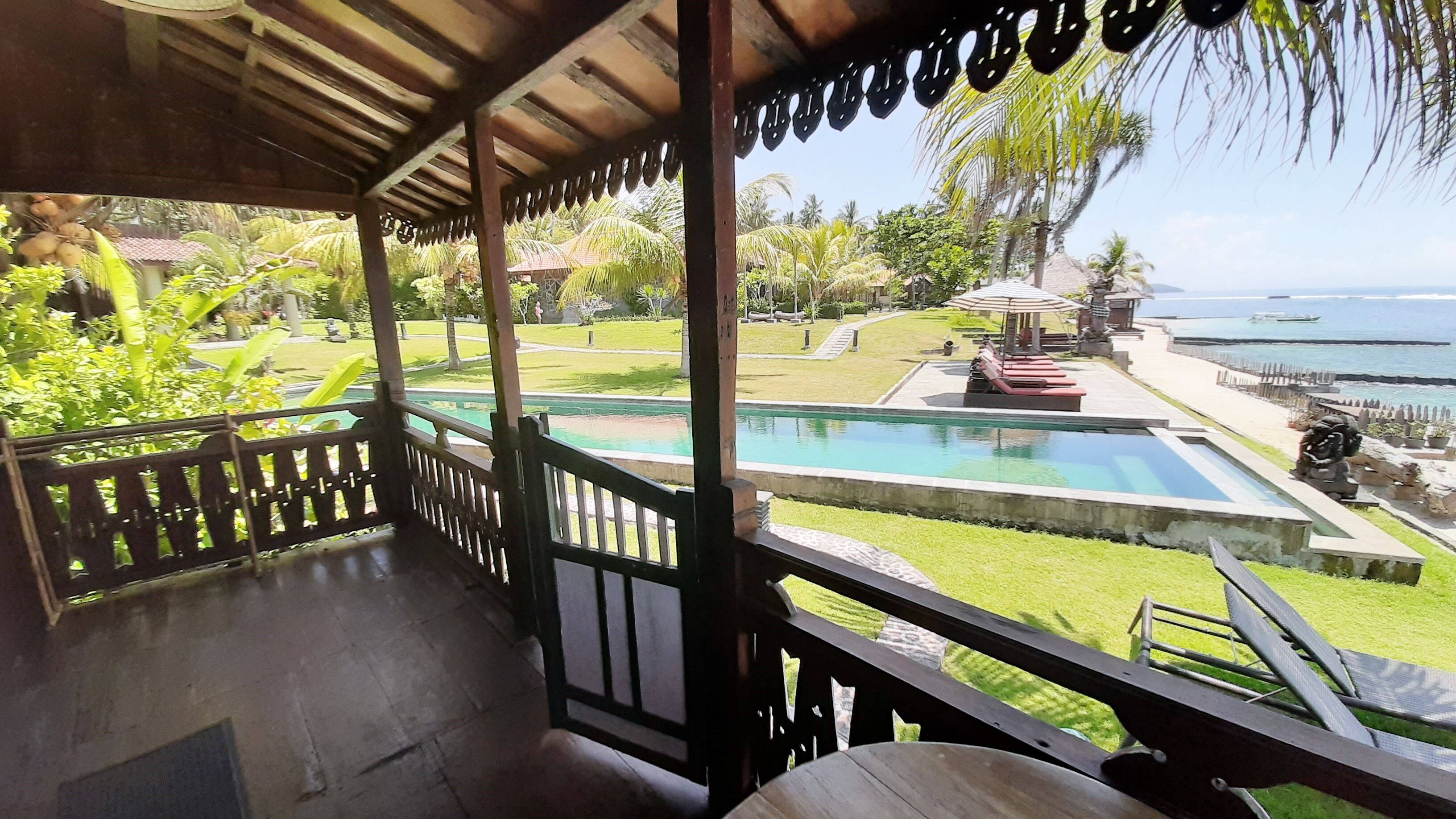 Un espacio al aire libre cubierto con piscina, sillones de descanso y vista al océano.