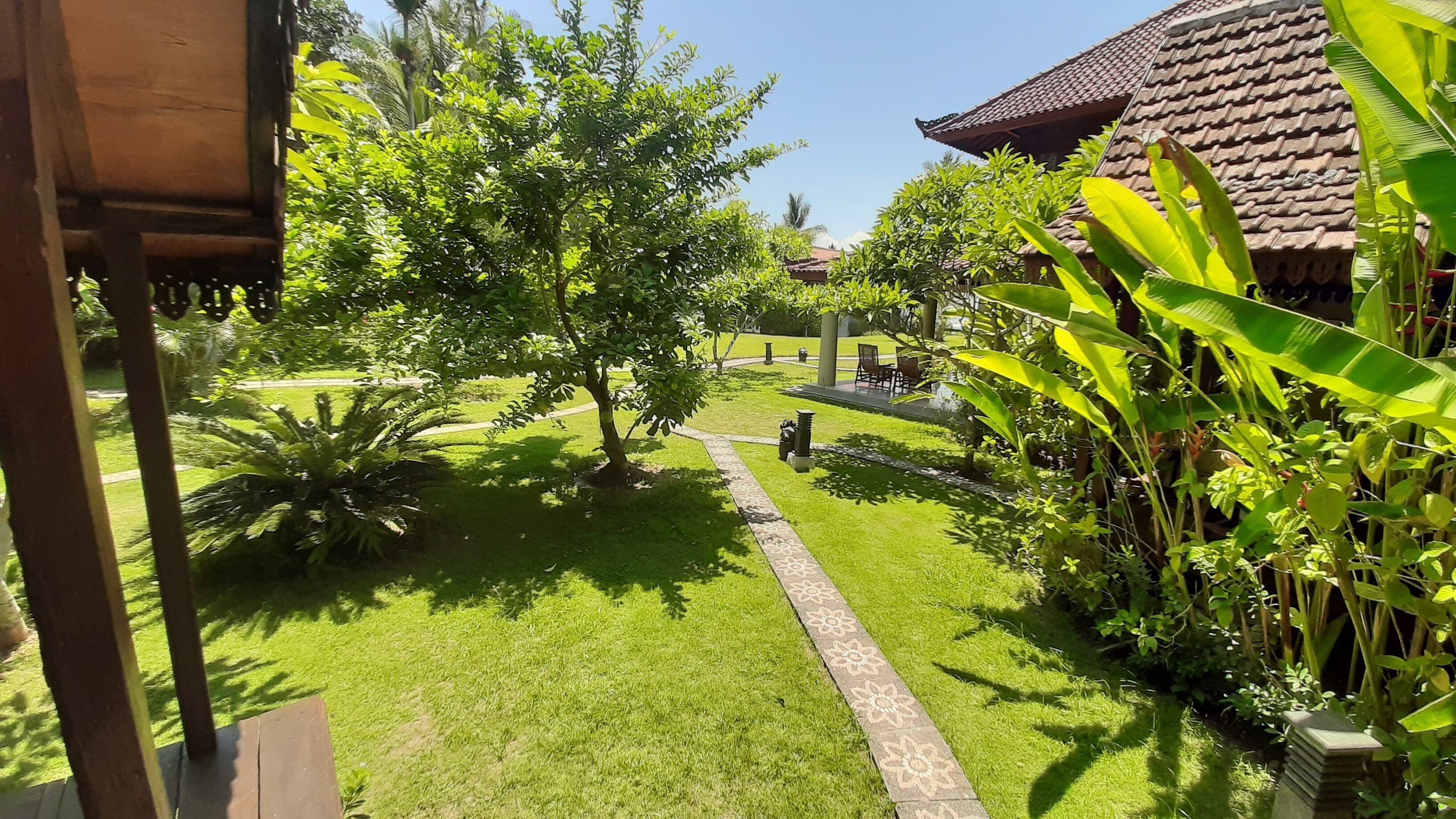 Ein gepflegter Garten mit einem Weg, üppigem Grün und einem traditionellen Gebäude mit Ziegeldach.