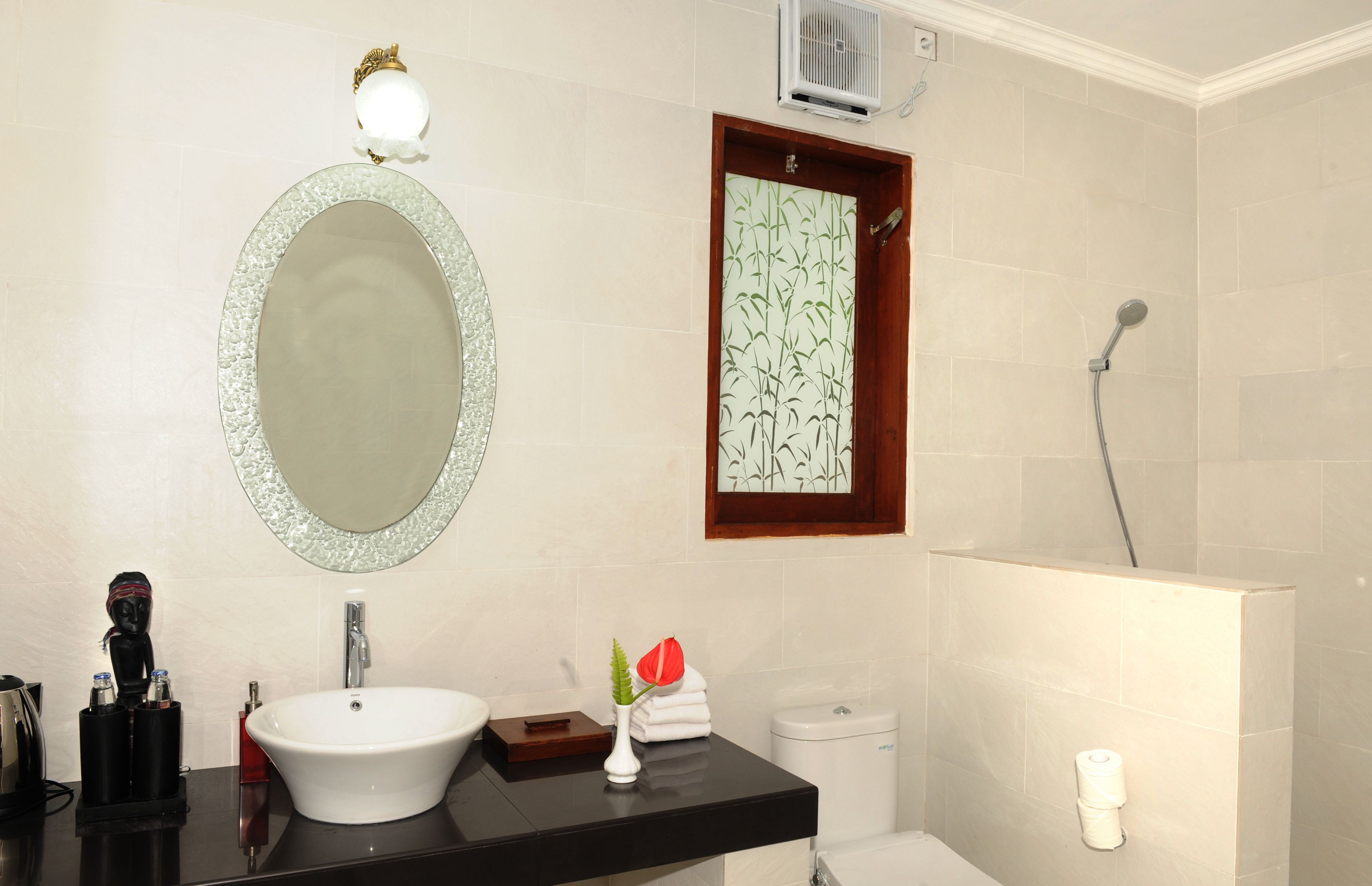 A bathroom with a white sink, a large mirror, a shower, and a toilet.
