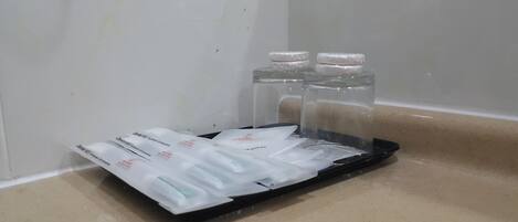 Una bandeja con artículos de cuidado dental y dos vasos de agua sobre una encimera.