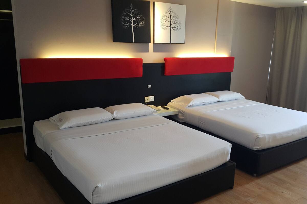 A hotel room with two beds, a red accent wall, and a modern design.
