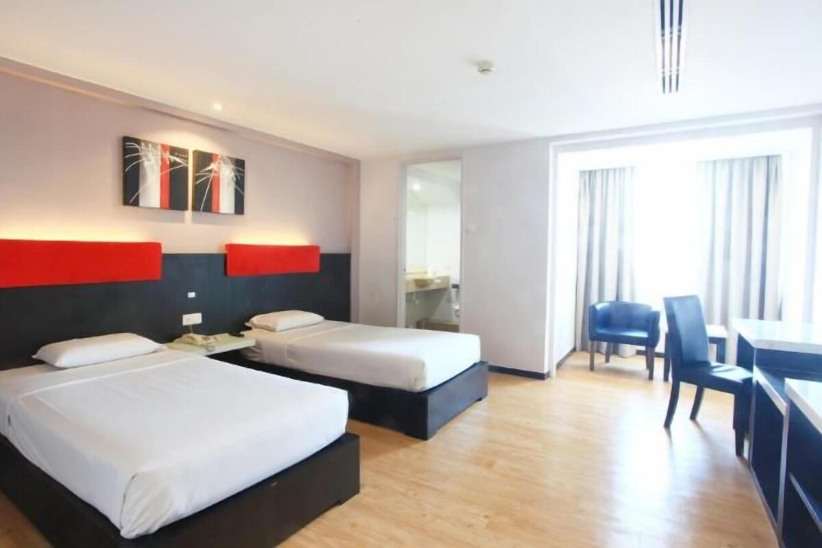 A hotel room with two beds, a desk, and a chair.