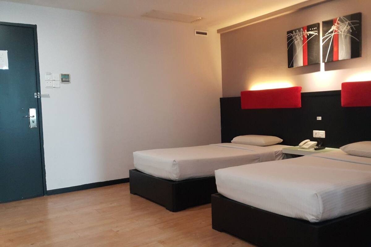 A hotel room with two beds, a desk with a phone, and a door.