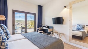 Habitació d'hotel amb un llit, escriptori, cadira, televisió i un mirall gran.