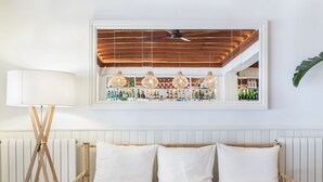 Habitació amb llit, lampada de peu i prestatgeria penjada a la paret amb ampolles.