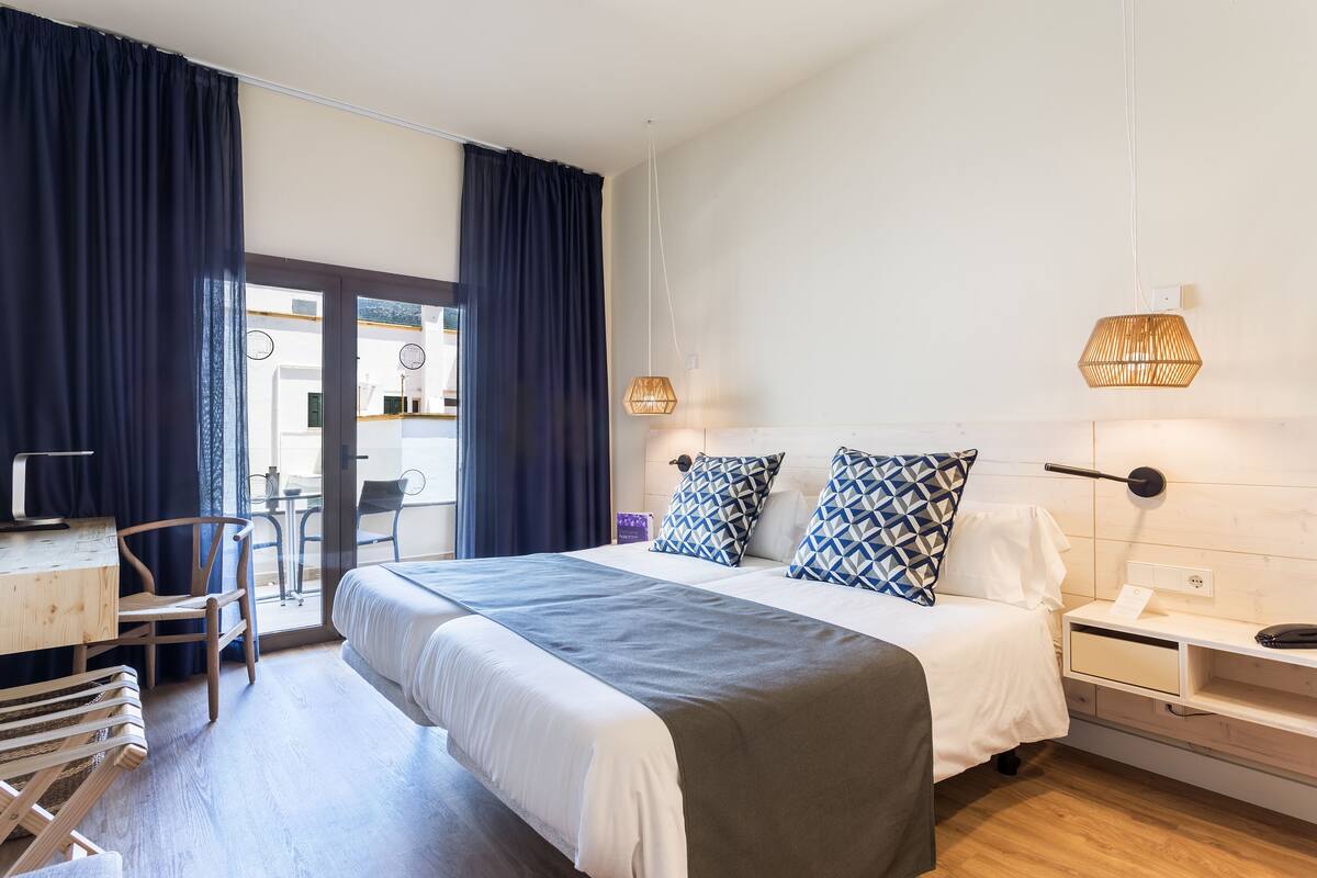 Ein modernes Hotelzimmer mit einem großen Bett, Nachttischen, einem Schreibtisch und einem Sessel.