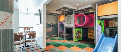 Zona de juegos infantiles con tobogán, red de escalada y estructuras coloridas.