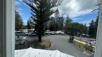 A view of a parking area with RVs, a large tree, and a building with a blue roof.