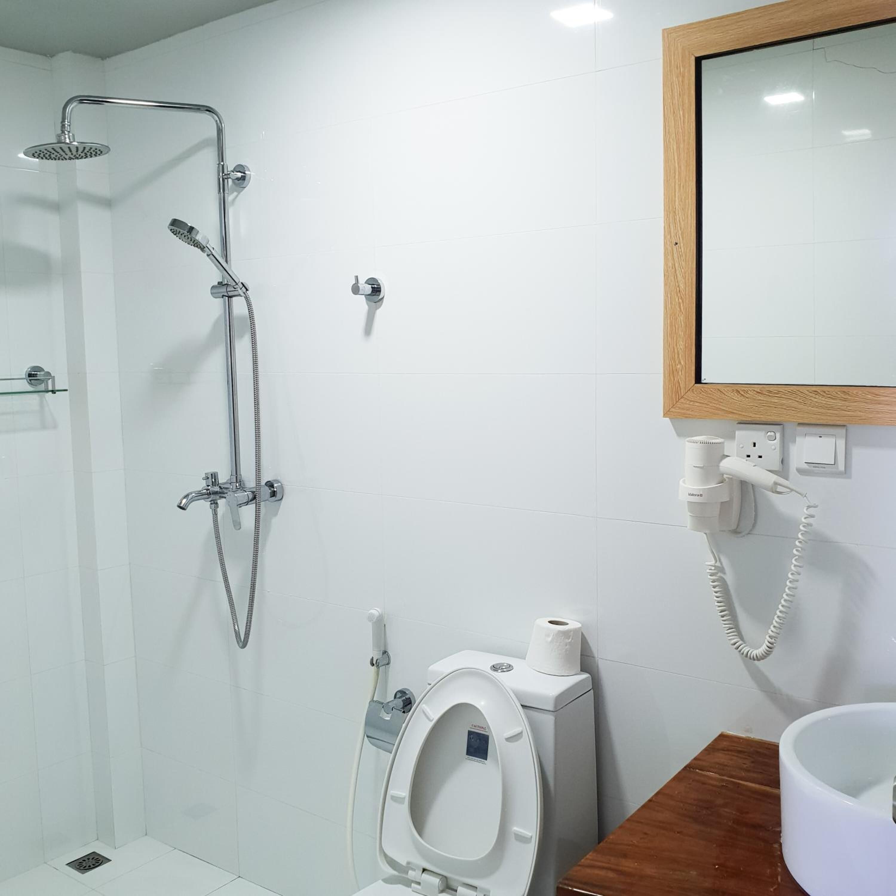 Une salle de bain avec une douche, des toilettes et un miroir.