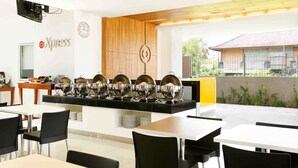 A modern dining area with a buffet setup, a clock, and a sign reading "Xpress". - Amaris Hotel Sunset Road (Kuta)