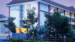 A modern hotel with a prominent entrance, multiple floors, and lush greenery in front. - Amaris Hotel Sunset Road (Kuta)
