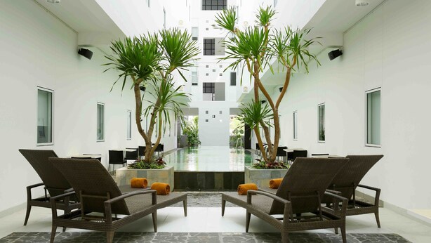 A modern conference room with a glass table, wicker chairs, and potted plants. - Amaris Hotel Sunset Road (Kuta)