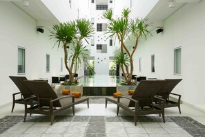 A modern conference room with a glass table, wicker chairs, and potted plants. - Amaris Hotel Sunset Road (Kuta)
