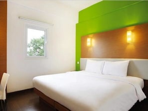 Une chambre d’hôtel moderne avec un grand lit, une fenêtre et un mur d’accent de couleur verte.