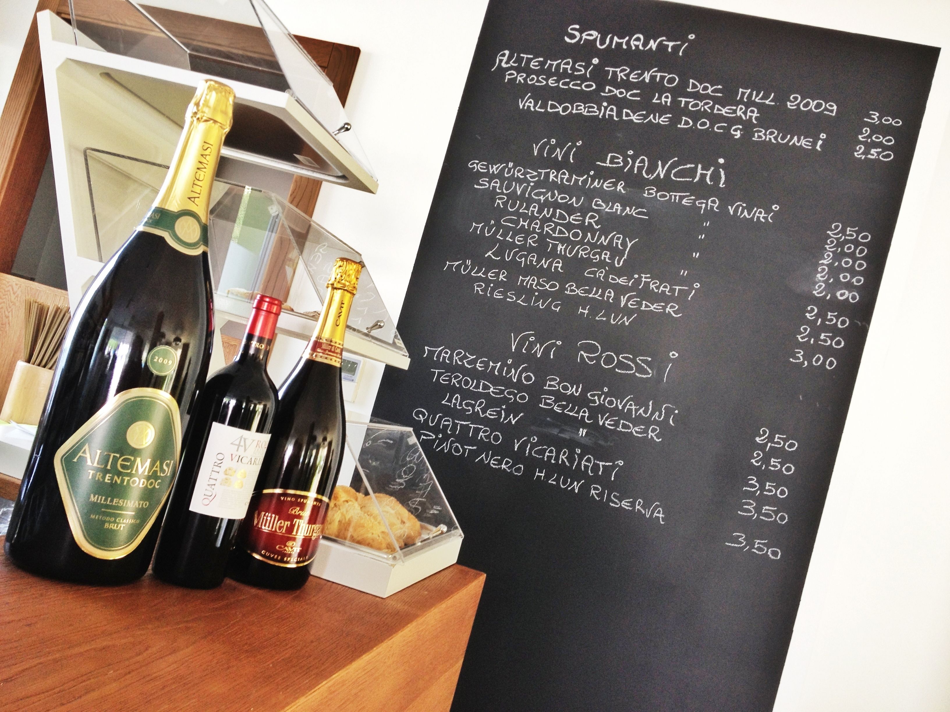 Three bottles of wine and a menu on a blackboard.