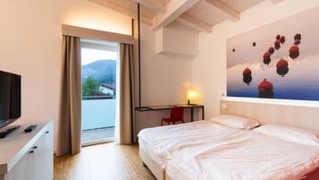 Une chambre d’hôtel avec un lit, un bureau, une chaise, une télévision et un tableau représentant des bouées accroché au mur.