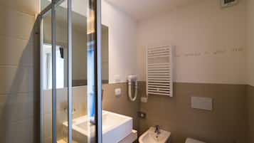 A modern bathroom with a glass shower enclosure, a white sink, a bidet, and a towel rack.