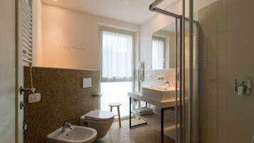 Un baño moderno con bidé, inodoro y lavamanos.