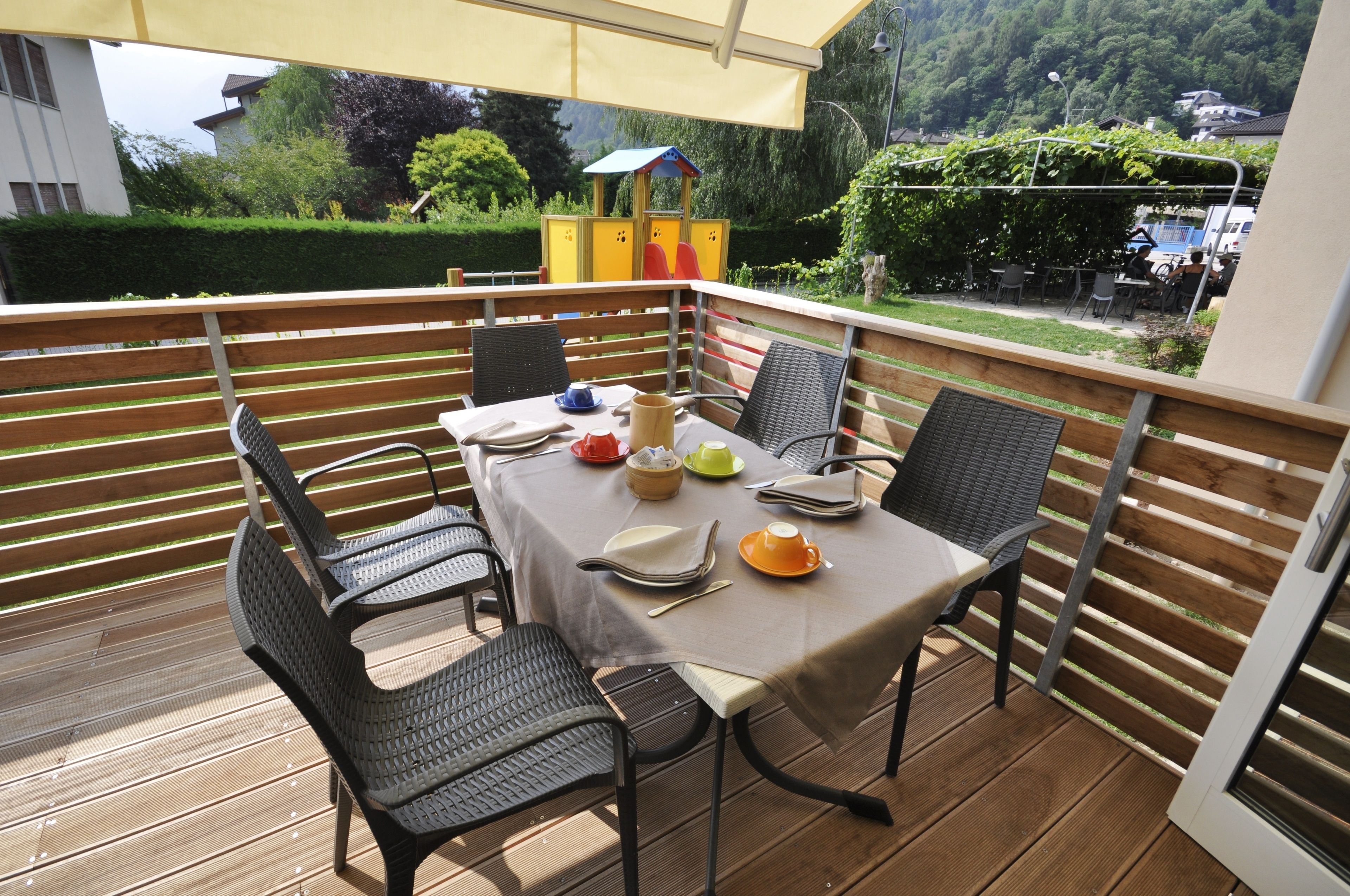 A covered outdoor dining area with a table set for four, surrounded by metal chairs.