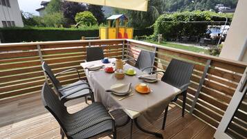 A covered outdoor dining area with a table set for four, surrounded by metal chairs.