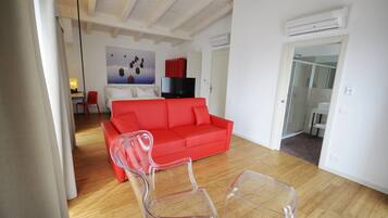 Una sala de estar moderna con un sofá rojo, un televisor y una mesa de centro de vidrio.